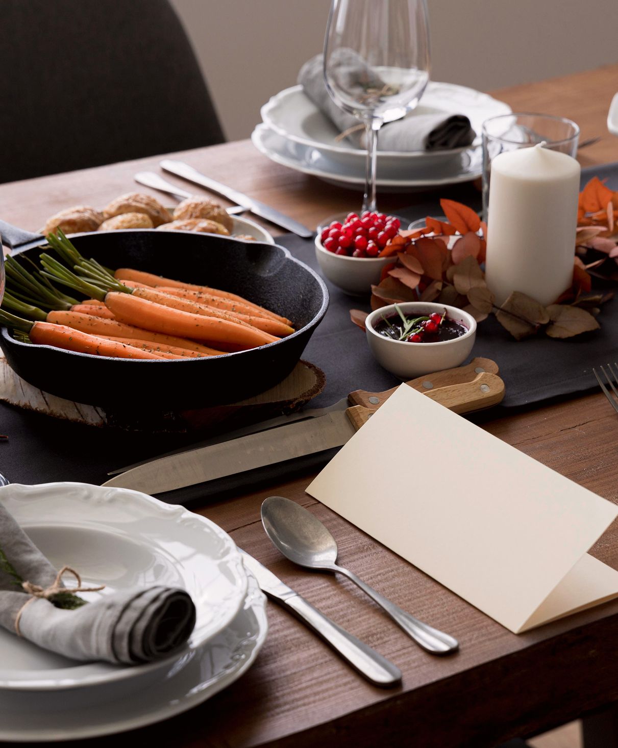 Dinner table arranged with cookware, place settings and food